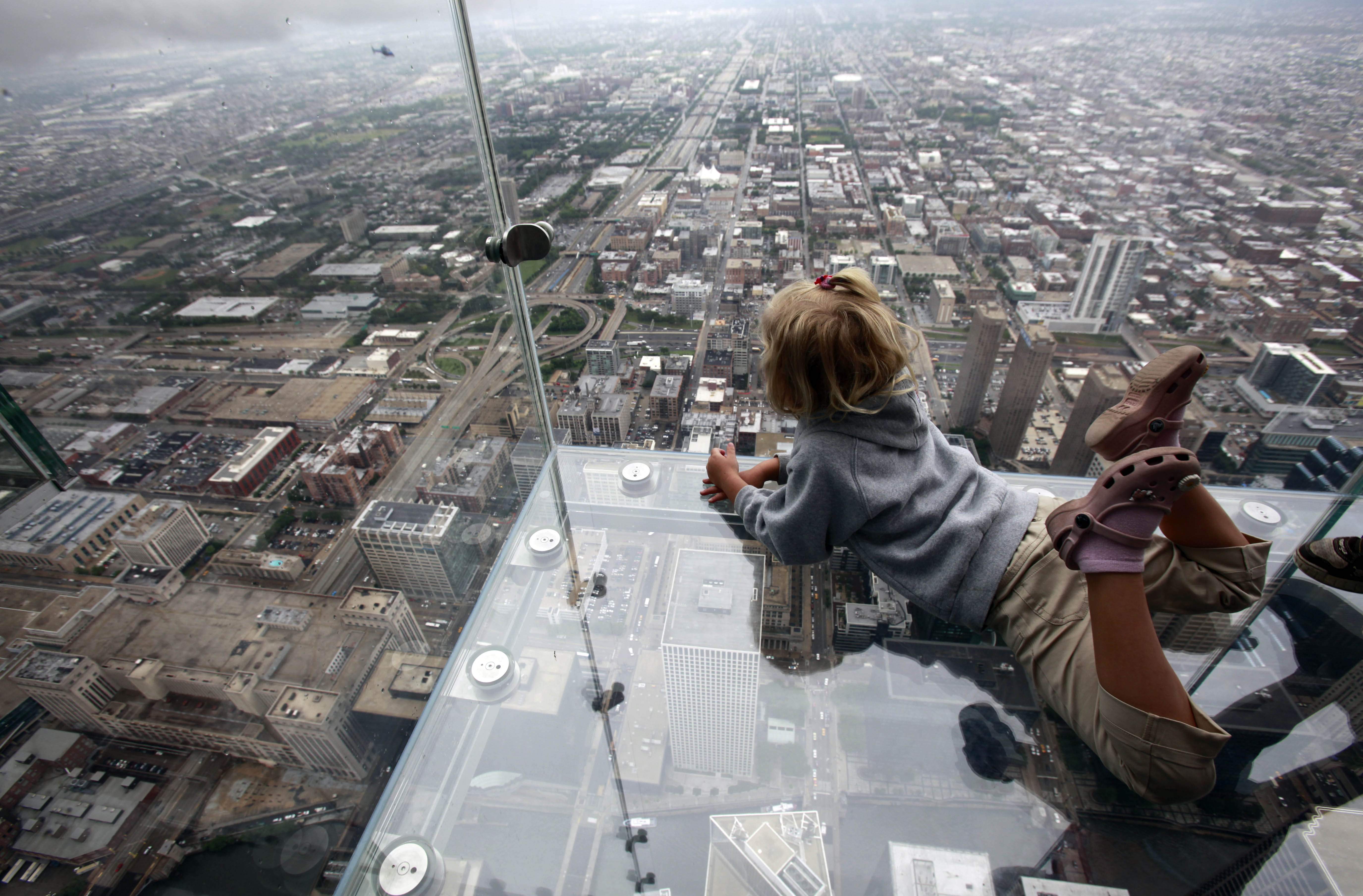 FILE – In this June 24, 2009, file photo Anna Kane, 5, of Alton, Ill. looks down from “The Ledge,” at the Sears Tower in Chicago. The glass balcony suspended 1,353 feet (412 meters) in the air and jut out 4 feet (1.22 meters) from the Sears Tower’s 103rd floor Skydeck, is one of the changes this year for the tallest building in the United State which will officially be renamed to Willis Tower, for the London-based Willis Group Holdings, on July 16, 2009. (AP Photo/Kiichiro Sato, File)